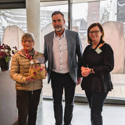 Besucherin, Bürgermeister und Geschäftsführerin bei der Geschenkübergabe