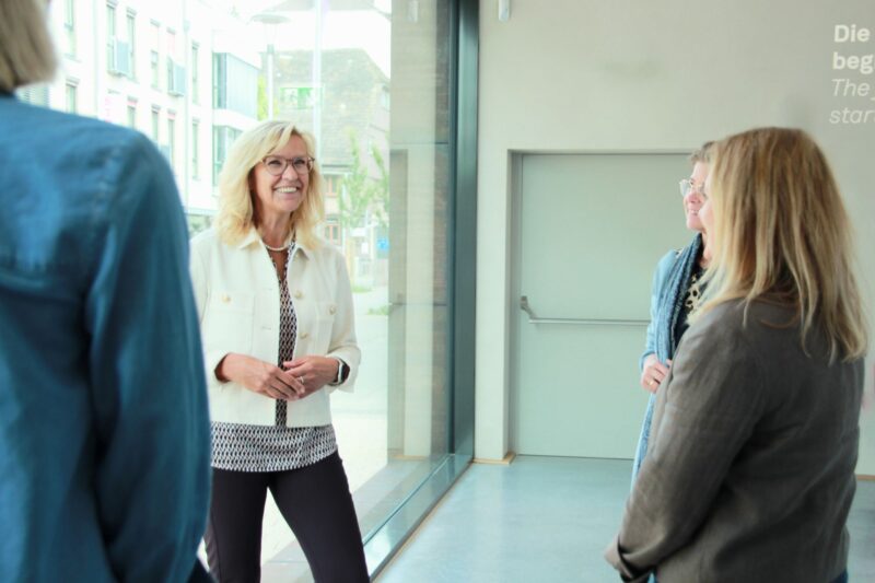 Frau steht als Ausstellungsguide vor einer Gruppe in Sensoria