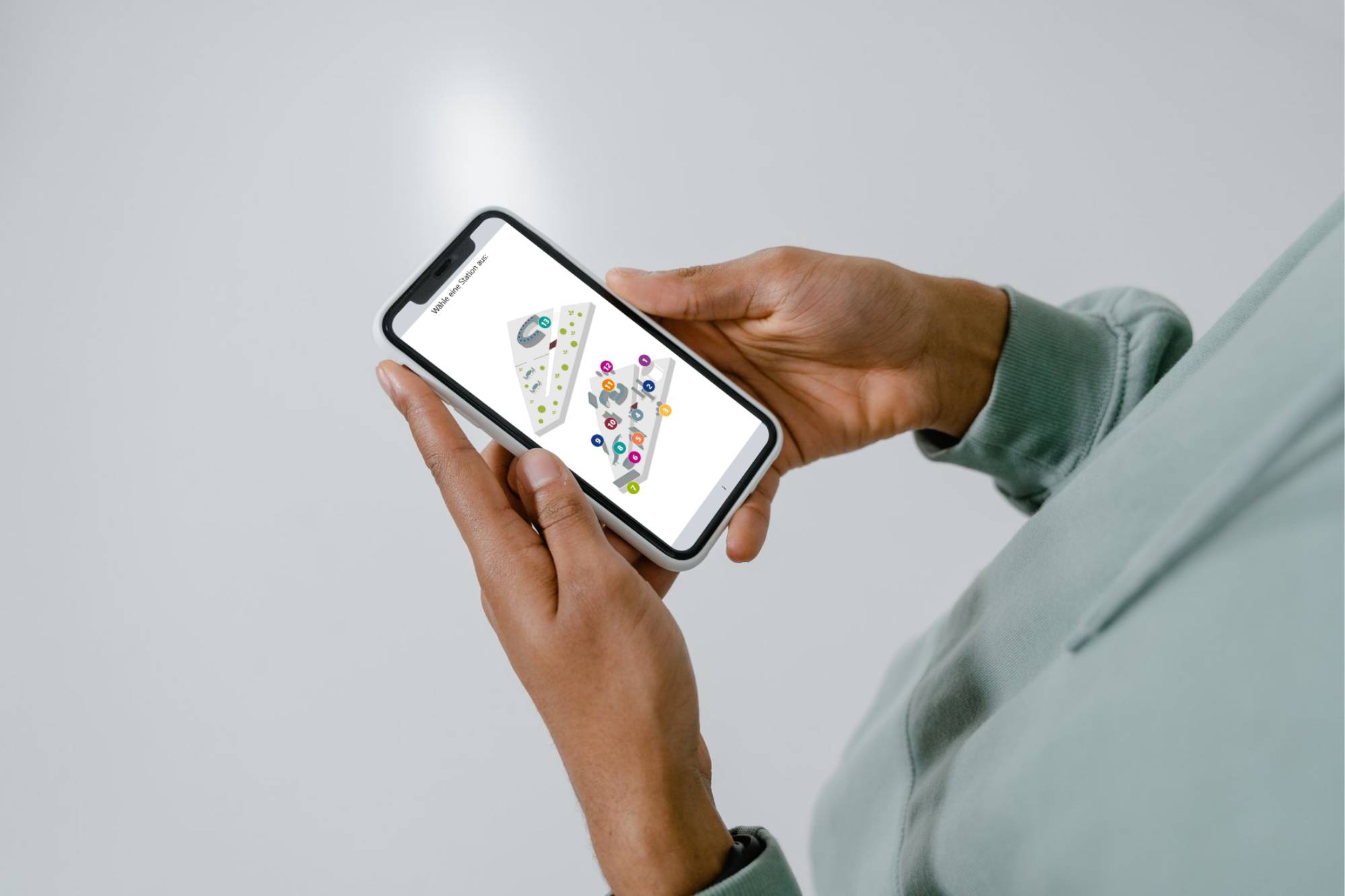 Person hält Smartphone in der Hand auf dem Display ist der Audioguide zusehen
