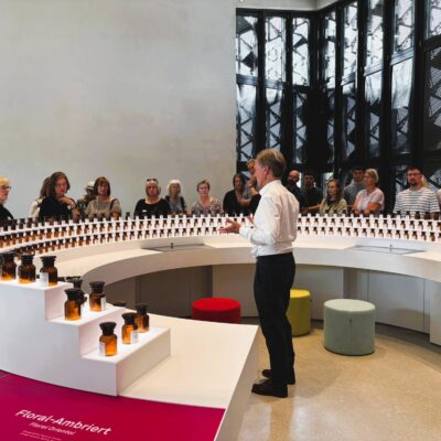 Architekt steht vor einer Gruppe in der Ausstellung und erklärt