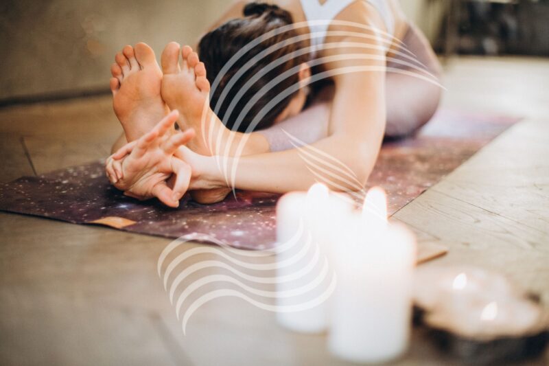 Frau mach Yoga, naben ihr stehen Kerzen